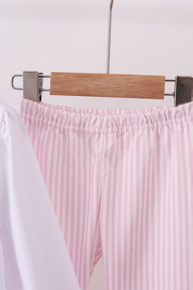 Pink striped pants on a hanger against a white background