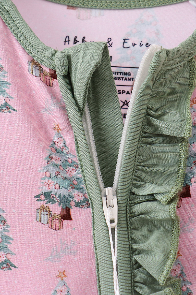 Close-up of a green zipper with ruffled details on a pink fabric background with Christmas tree designs.