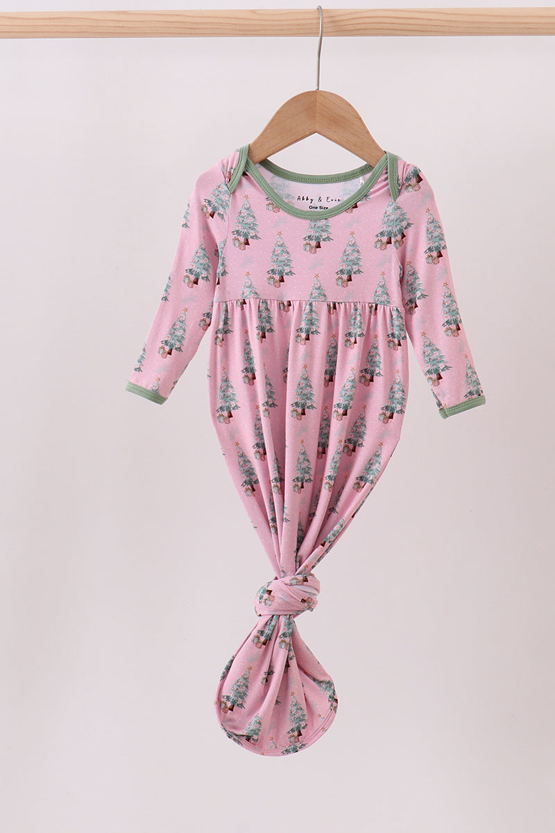Pink baby dress with tree pattern on a hanger against a light pink background