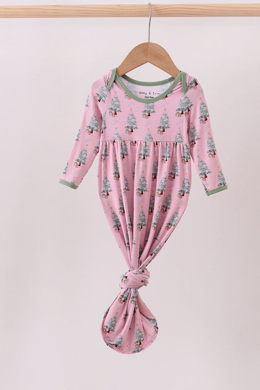 Pink baby dress with tree pattern on a hanger against a light pink background
