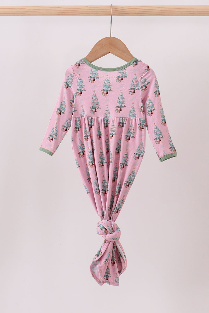 Pink baby dress with tree pattern on a hanger against a white background