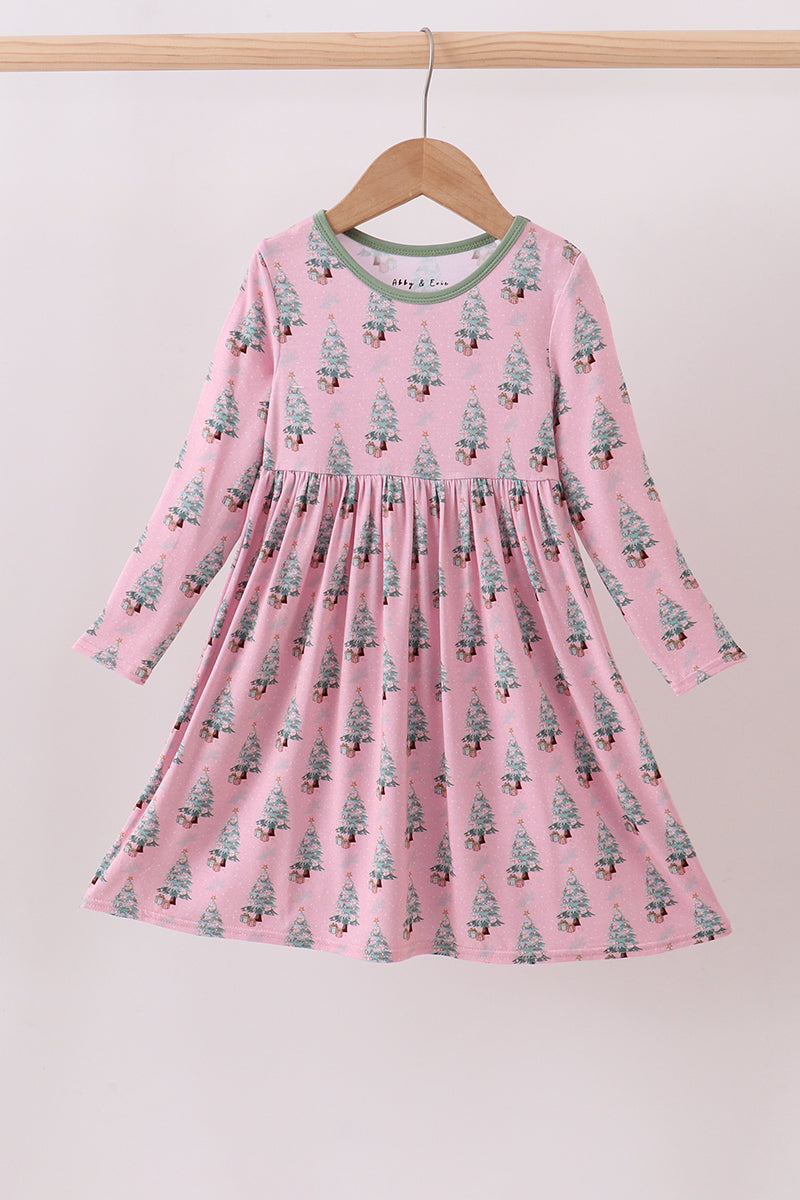 Pink dress with tree pattern on a hanger against a light background