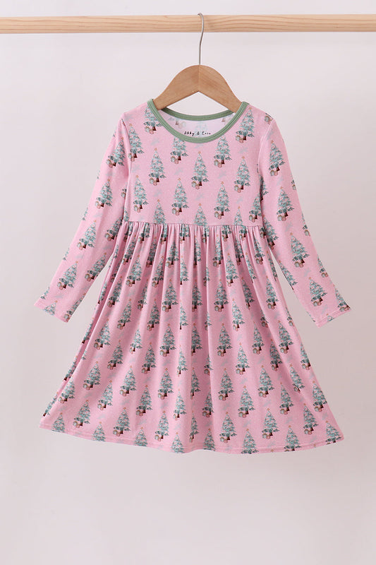 Pink dress with tree pattern on a hanger against a light background