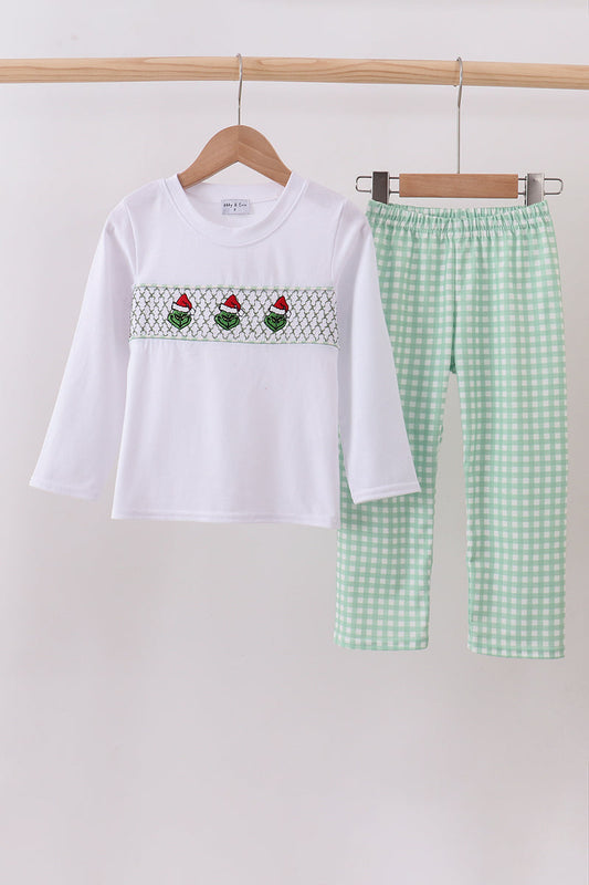 White top with embroidered design and green checkered pants on a hanger against a white background