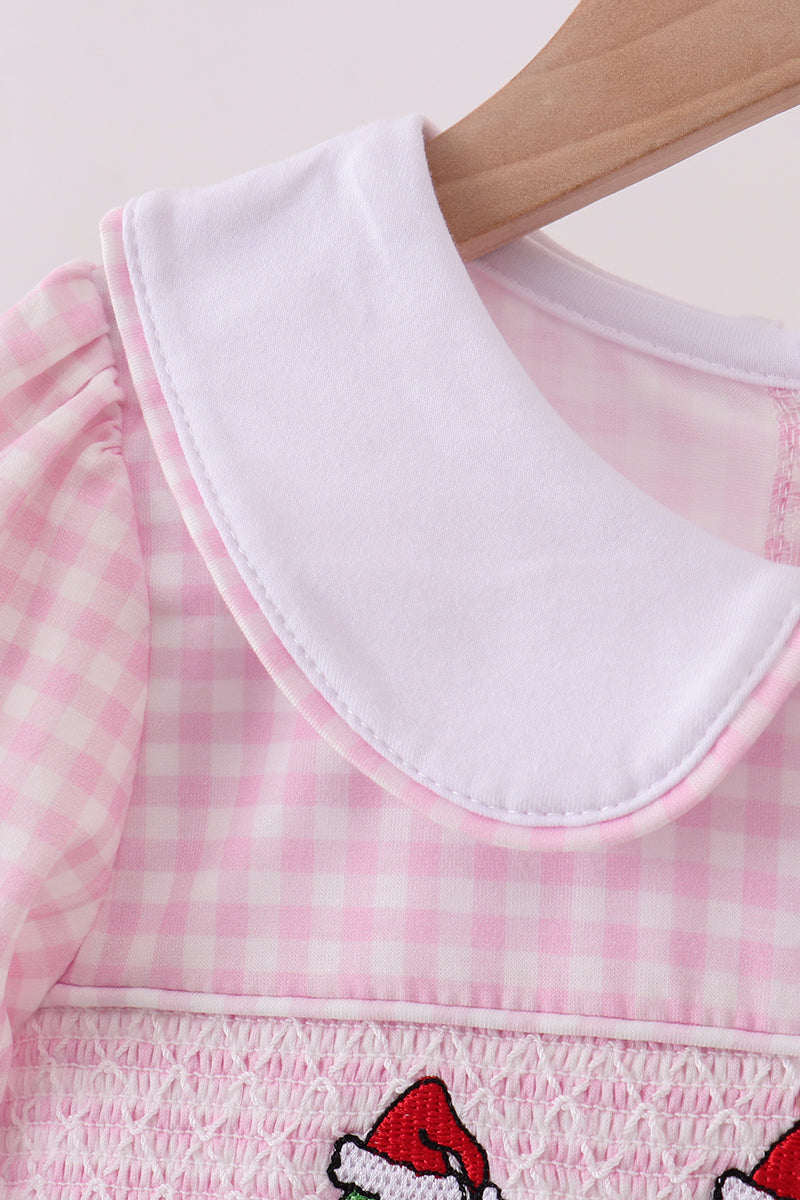 Close-up of a pink checkered dress with a white collar and Santa Claus design on a light background.