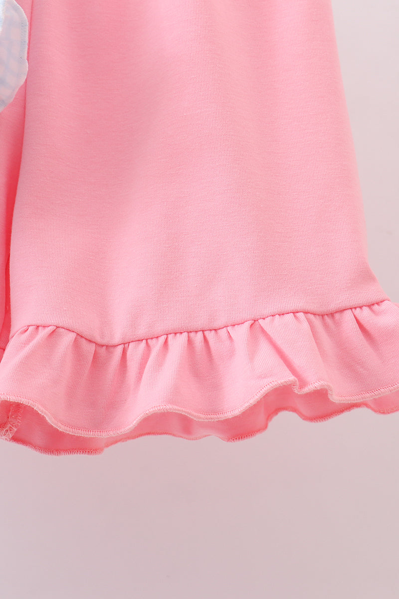Close-up of a pink dress with ruffled hem on a light background
