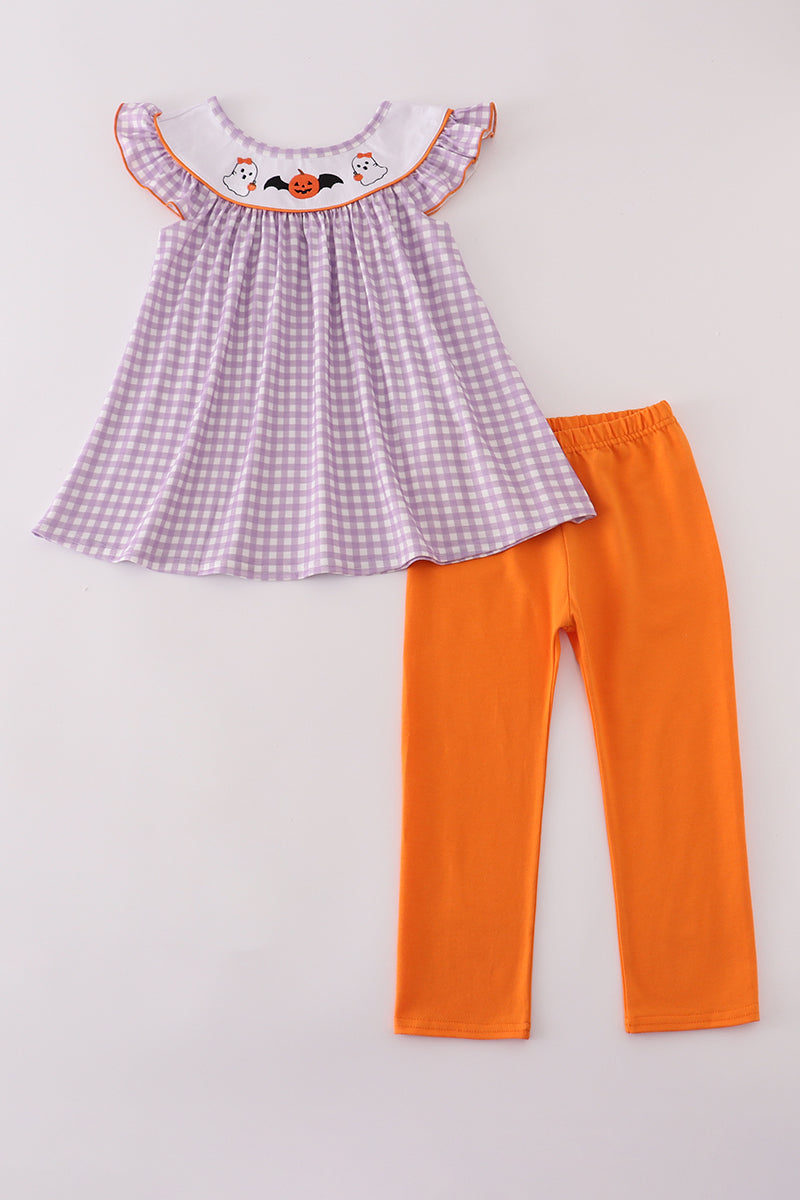 Purple checkered top and orange pants on a light gray background