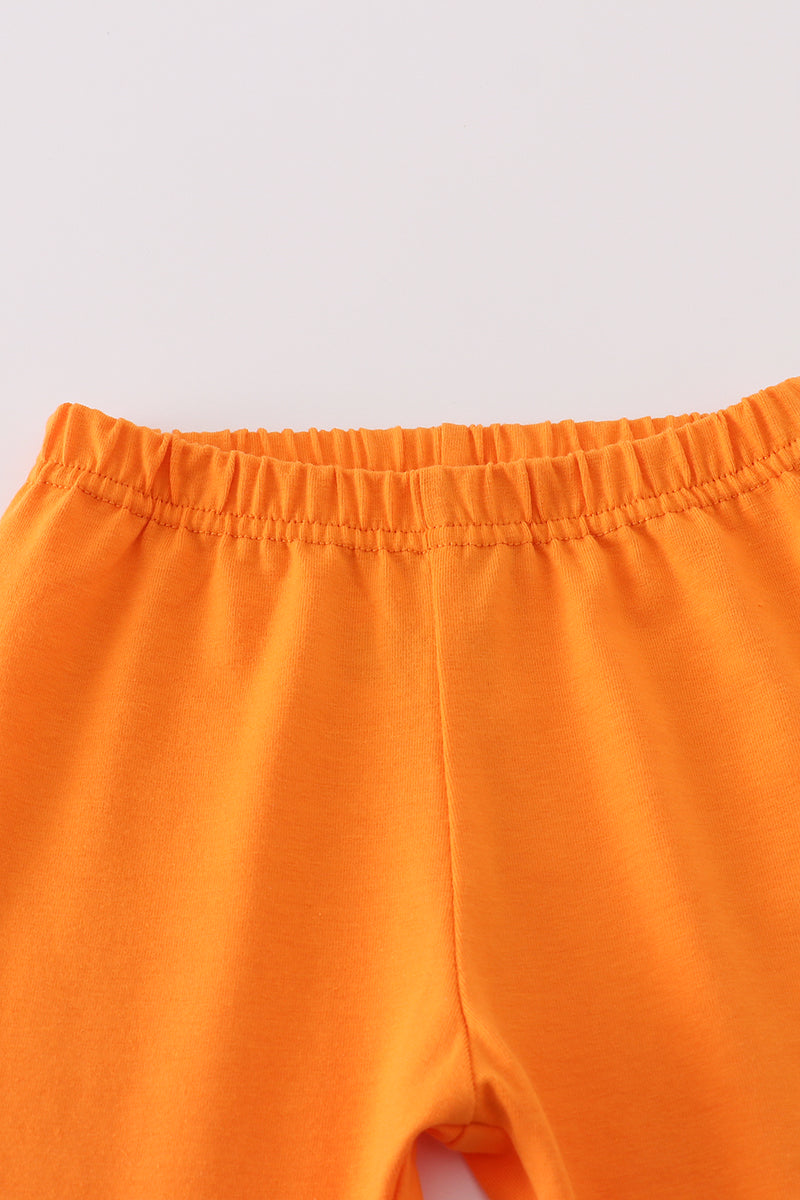 Close-up of orange pants on a light gray background