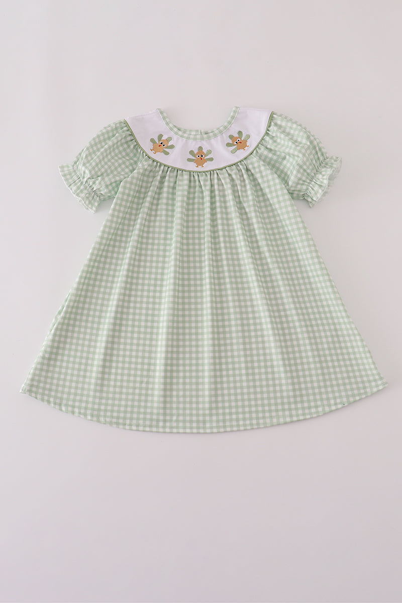Green checkered dress with embroidered details on a light gray background