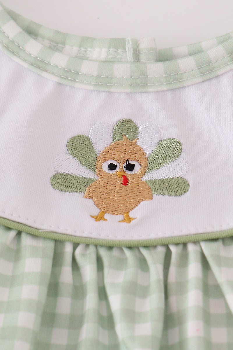 Children's apron with a embroidered turkey design on a green and white checkered background