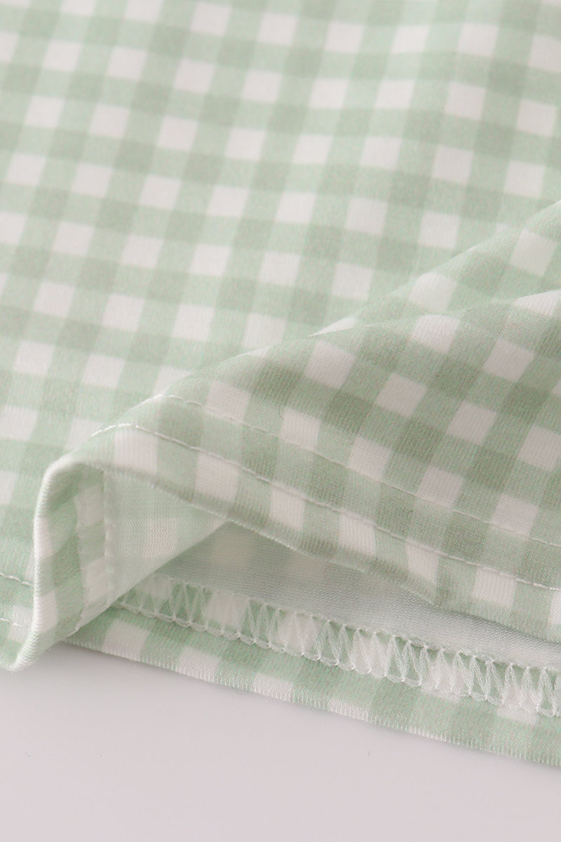 Green and white checkered fabric with a folded edge on a light gray background