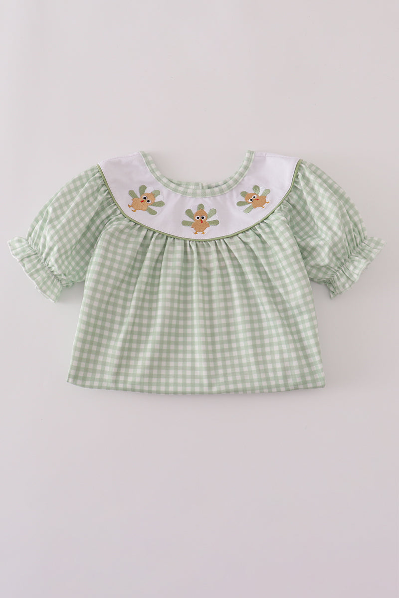 Green checkered blouse with embroidered details on a light gray background