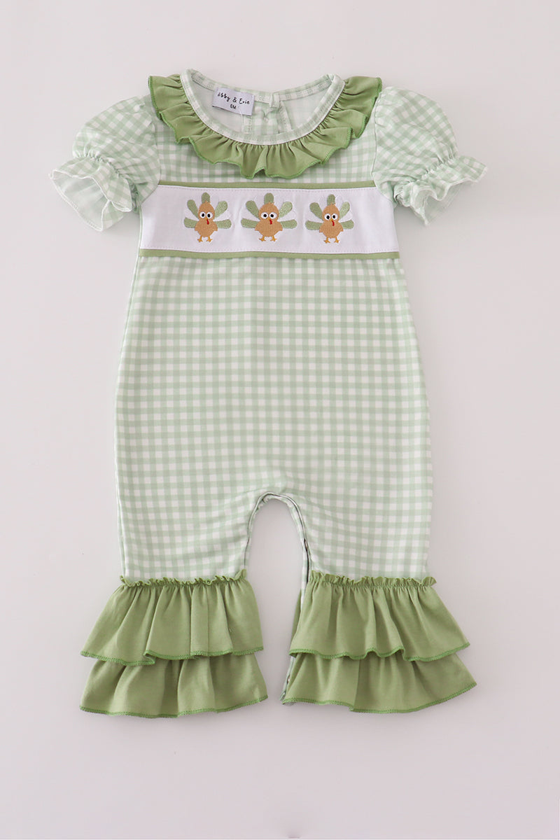 Green checkered baby romper with ruffled details on a white background