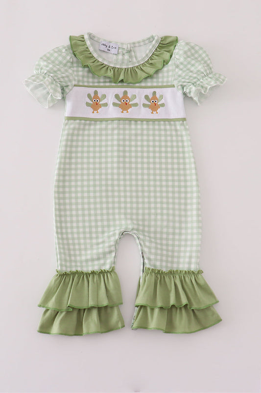 Green checkered baby romper with ruffled details on a white background