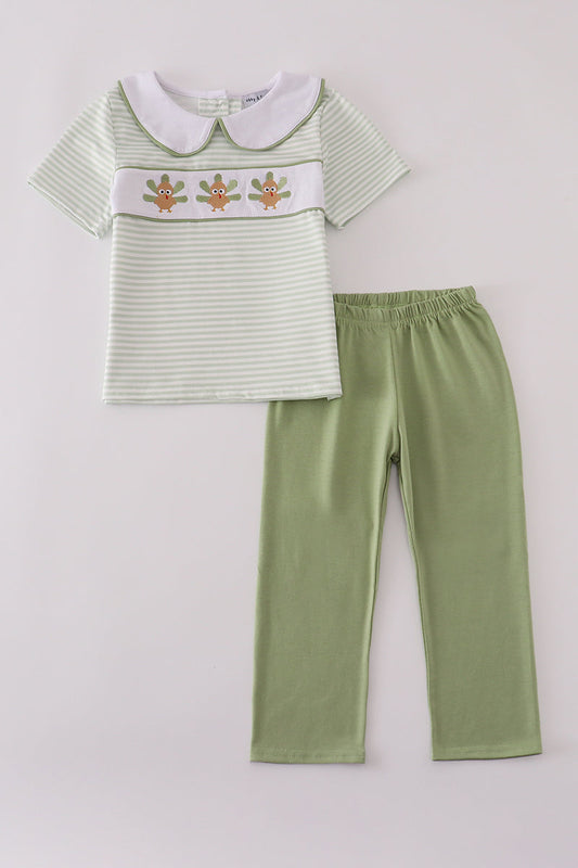 Children's outfit with striped shirt and green pants on a light gray background
