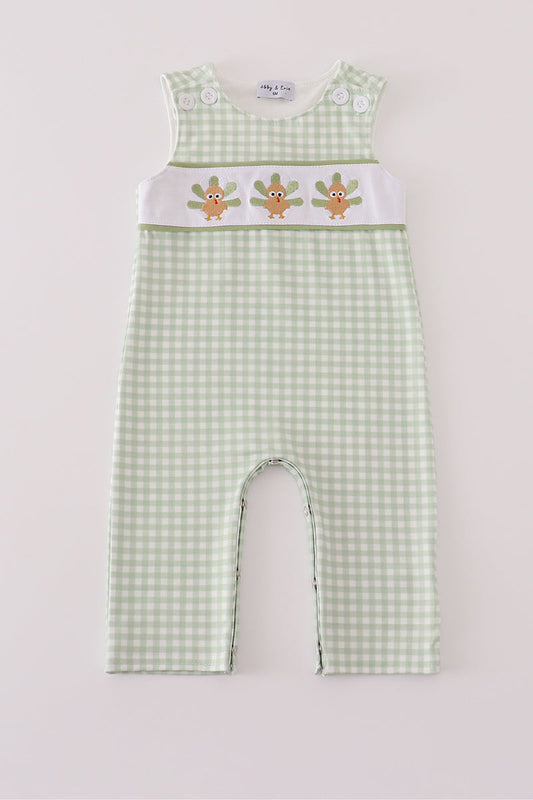 Green checkered baby romper with embroidered design on a light gray background