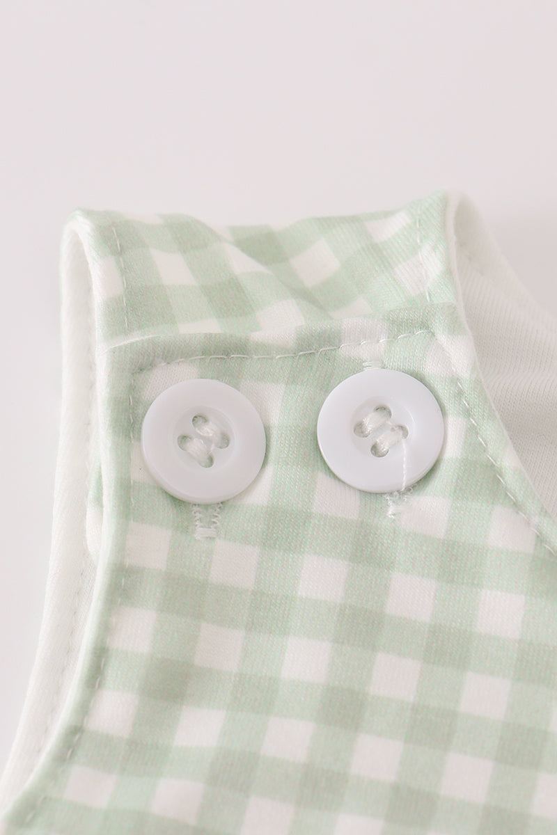 Green checkered fabric with two white buttons on a light gray background