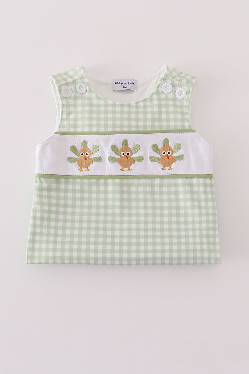 Green checkered baby dress with embroidered designs on a white background