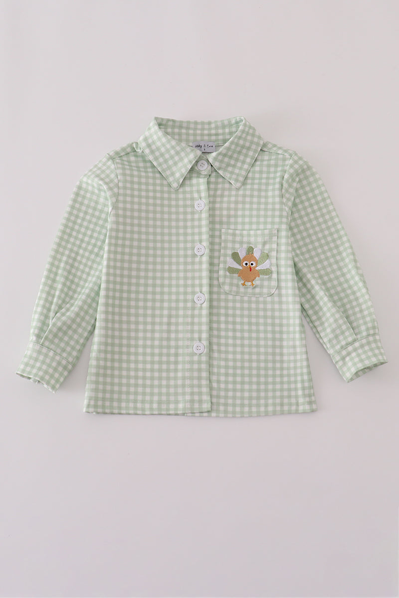Green checkered shirt with a embroidered design on a light gray background