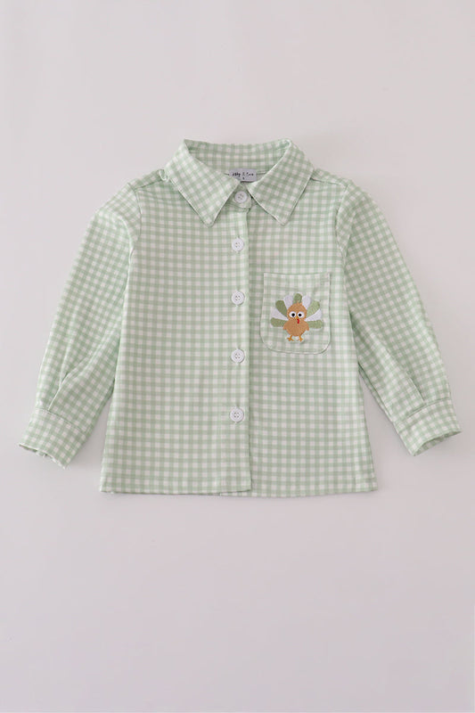 Green checkered shirt with a embroidered design on a light gray background