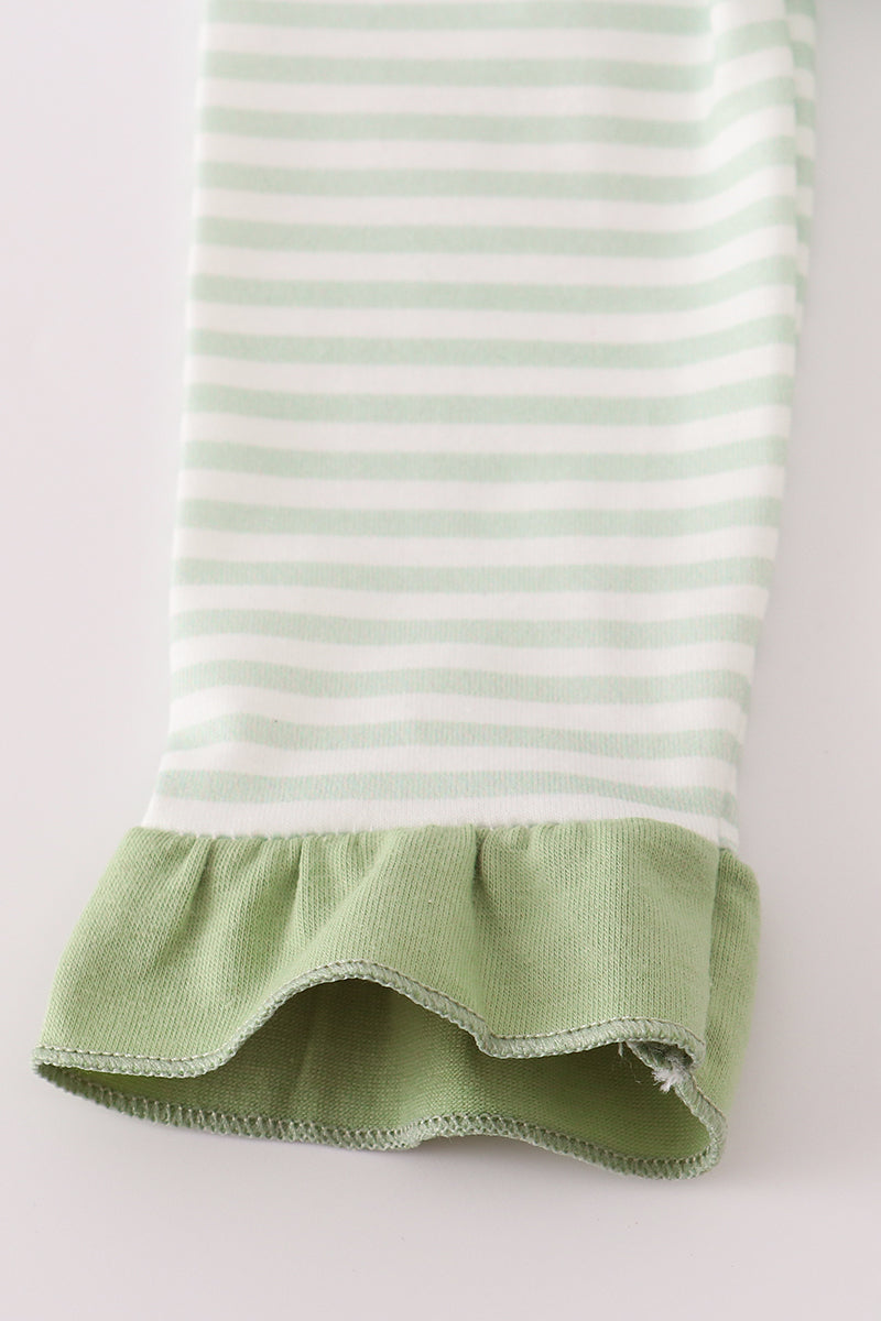 Green and white striped fabric with a ruffled edge on a light gray background
