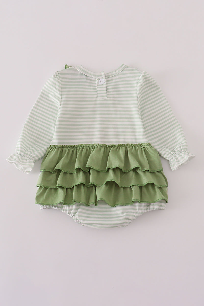 Green and white striped baby romper with ruffled skirt on a light purple background