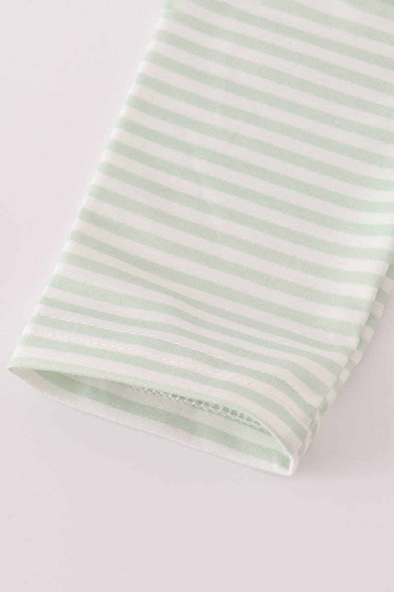 Folded green and white striped fabric on a light gray background