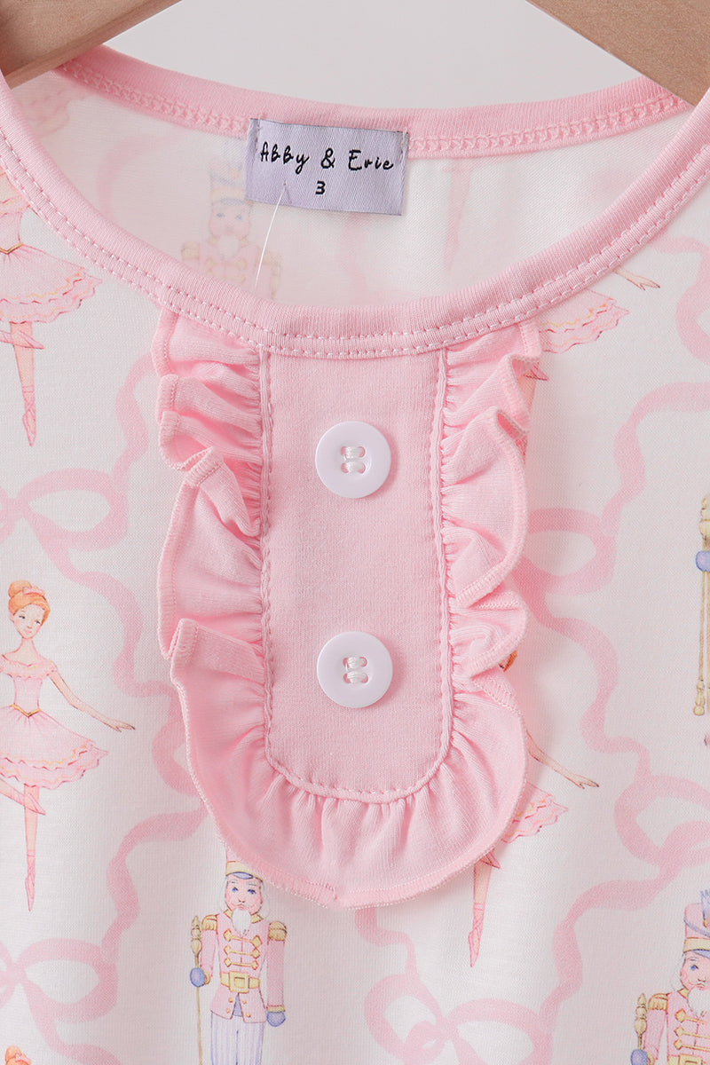 Close-up of a baby outfit with ruffled collar and buttons, featuring a brand label.