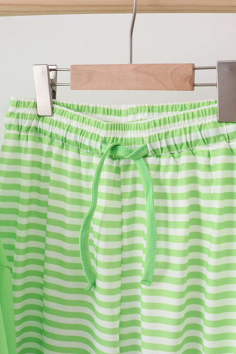 Green and white striped shorts on a hanger against a light background