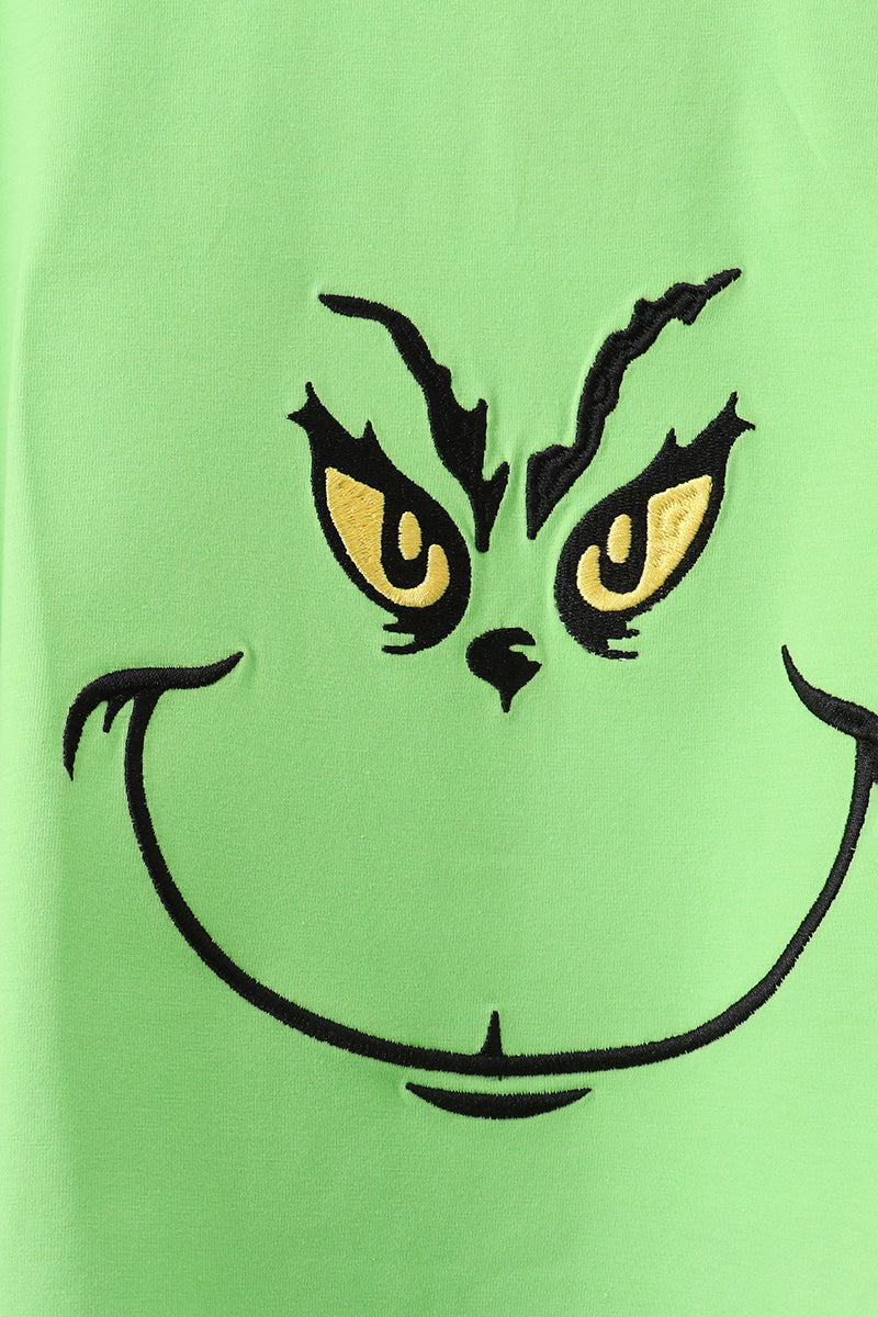 Close-up of a green shirt with a Grinch face design.
