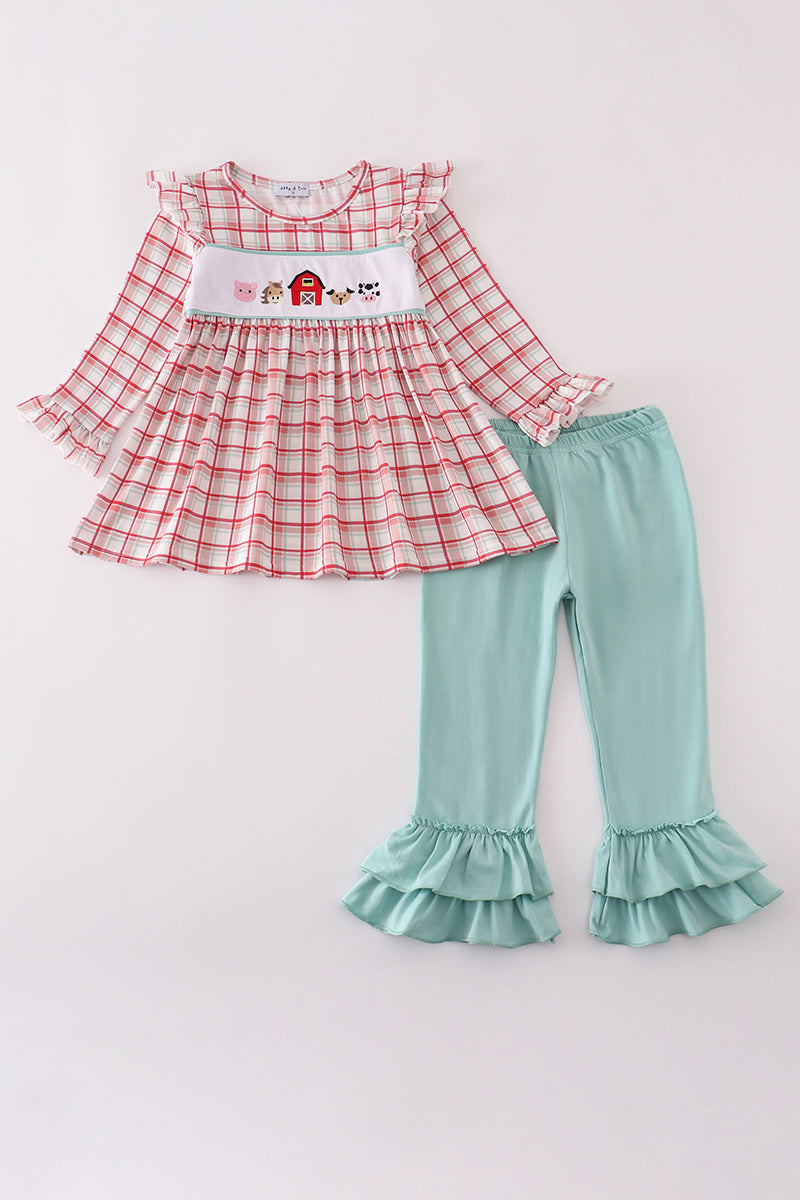 Red plaid top and teal ruffled pants set on a white background