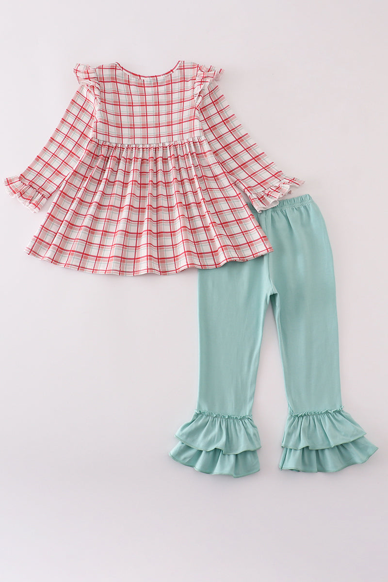 Red plaid top and green ruffled pants on a light gray background