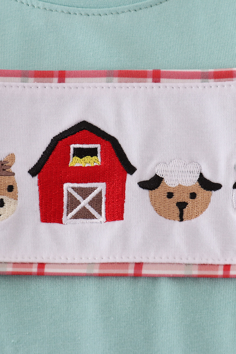 Close-up of a children's outfit with farm-themed design on a light blue background