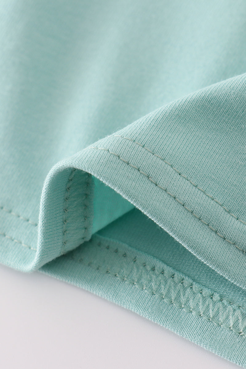 Close-up of teal fabric with a visible seam on a light gray background