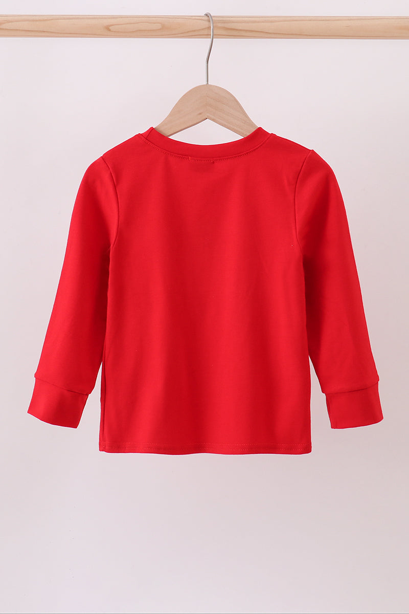 Red long-sleeve shirt on a wooden hanger against a light pink background