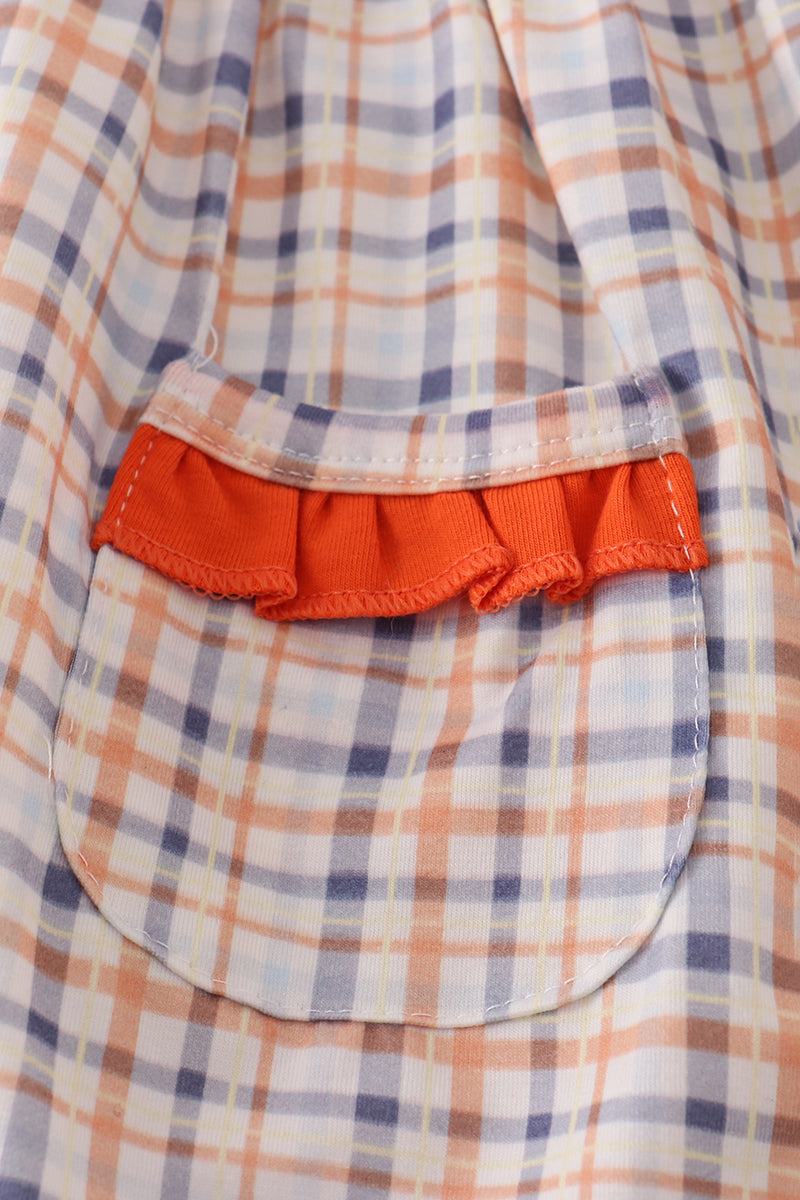 Close-up of a plaid shirt with a red pocket on a matching fabric background