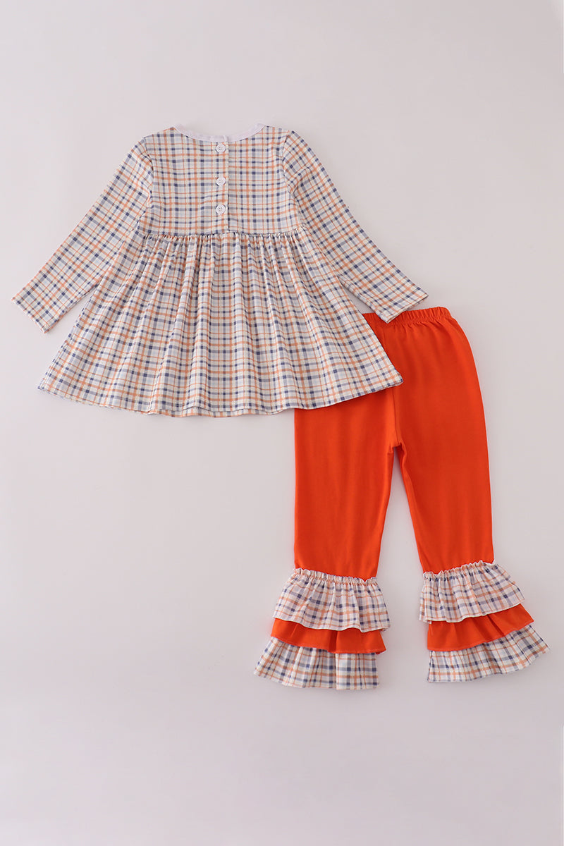 Plaid top and orange pants with ruffled hem on a light gray background