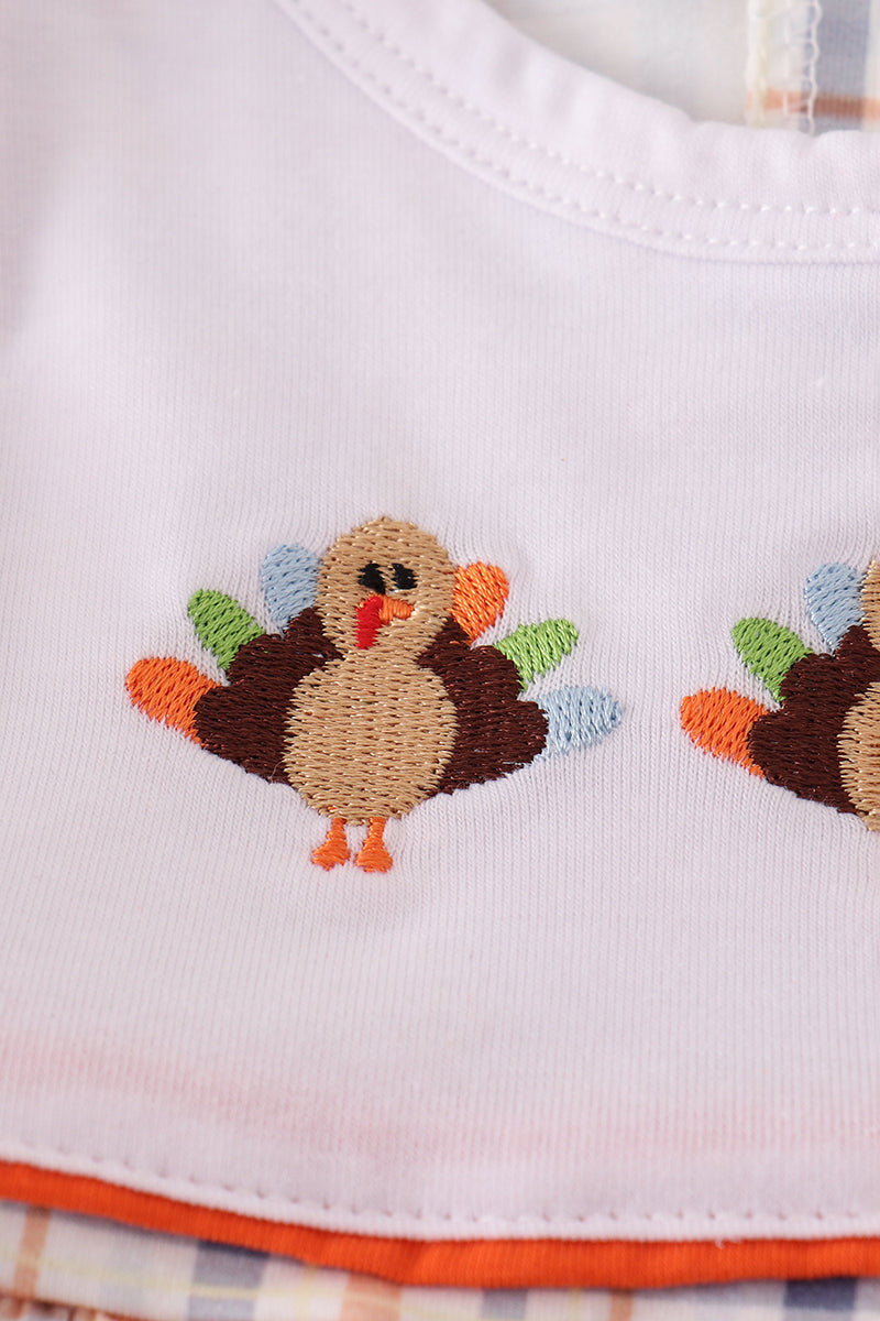 Embroidered turkey design on a white fabric with plaid trim
