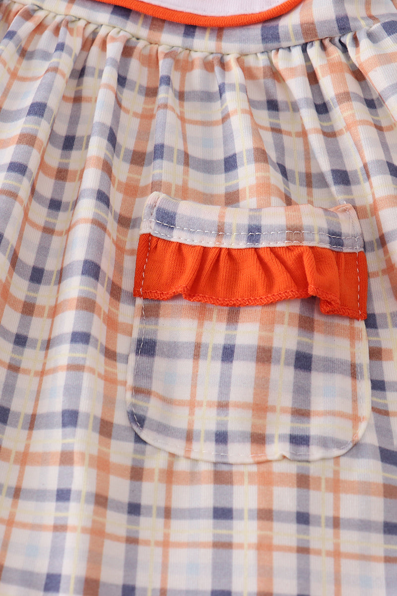 Close-up of a plaid dress with a red pocket and trim.
