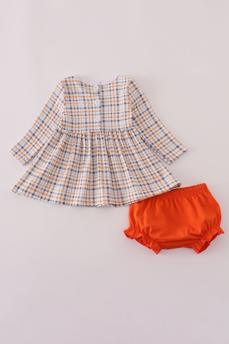 Plaid dress and orange bloomers on a light gray background
