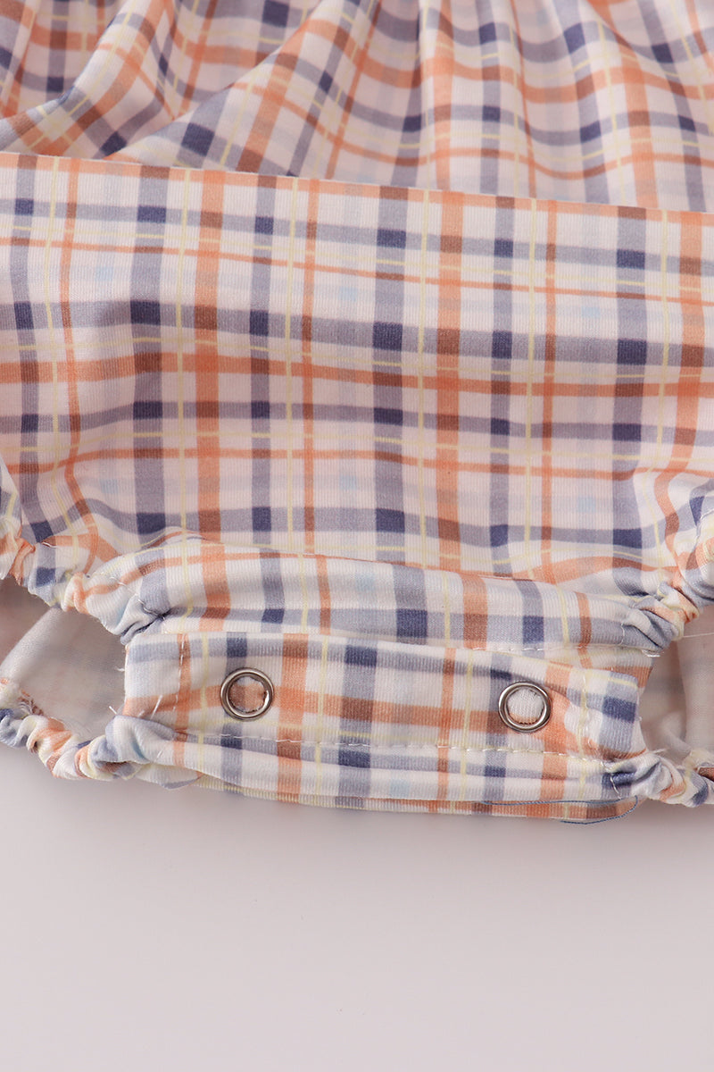 Plaid-patterned baby romper with button closures on a light gray background