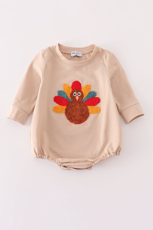 Beige baby romper with a colorful turkey design on a white background