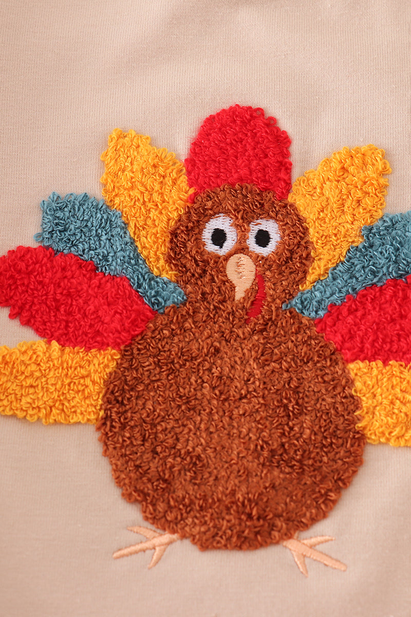 Decorative patch of a turkey with colorful feathers on a beige background