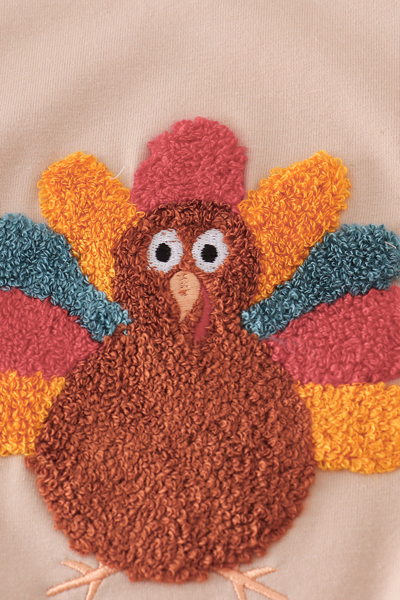 Textured patch of a turkey with colorful feathers on a beige background