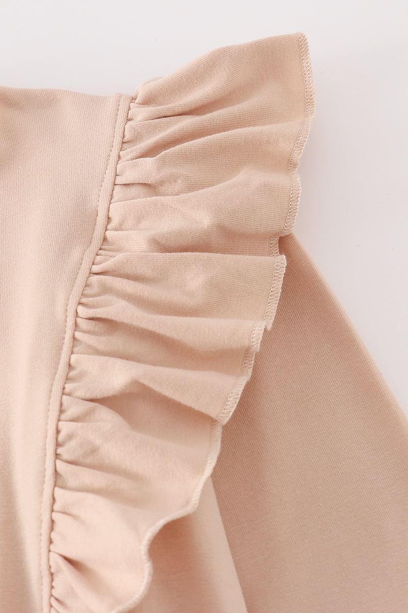 Close-up of a beige fabric with ruffled edge on a light background