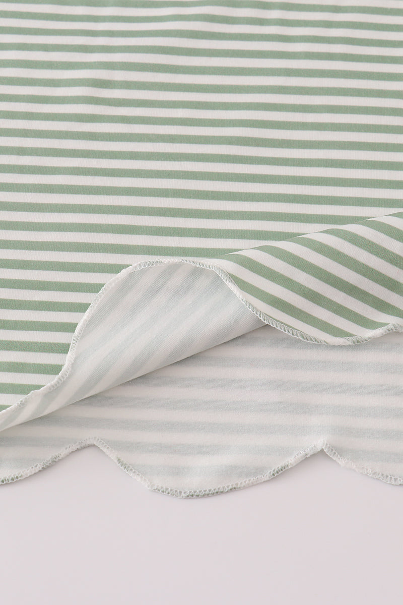 Close-up of a fabric with green and white horizontal stripes on a light gray background