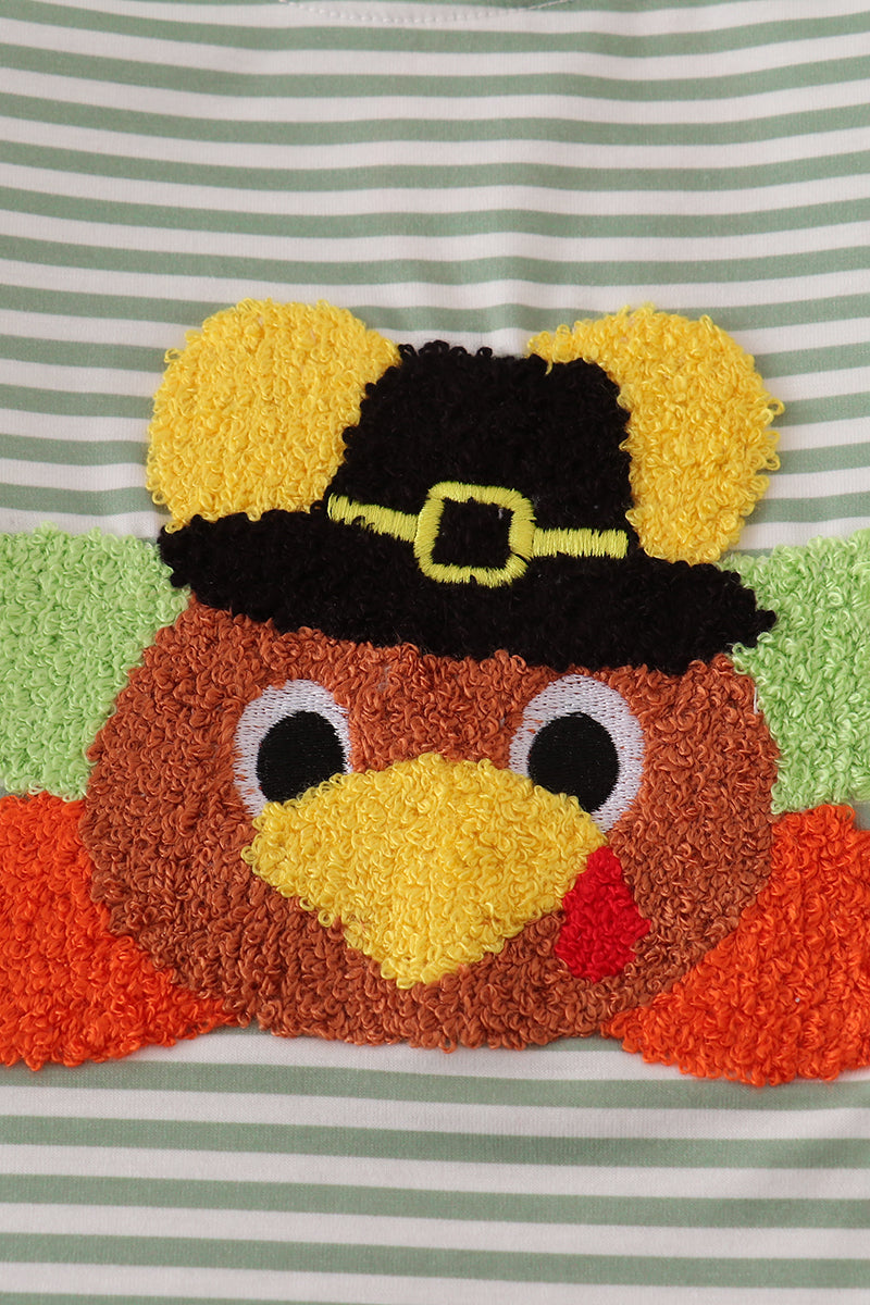 Decorative patch of a turkey wearing a pilgrim hat on a striped background