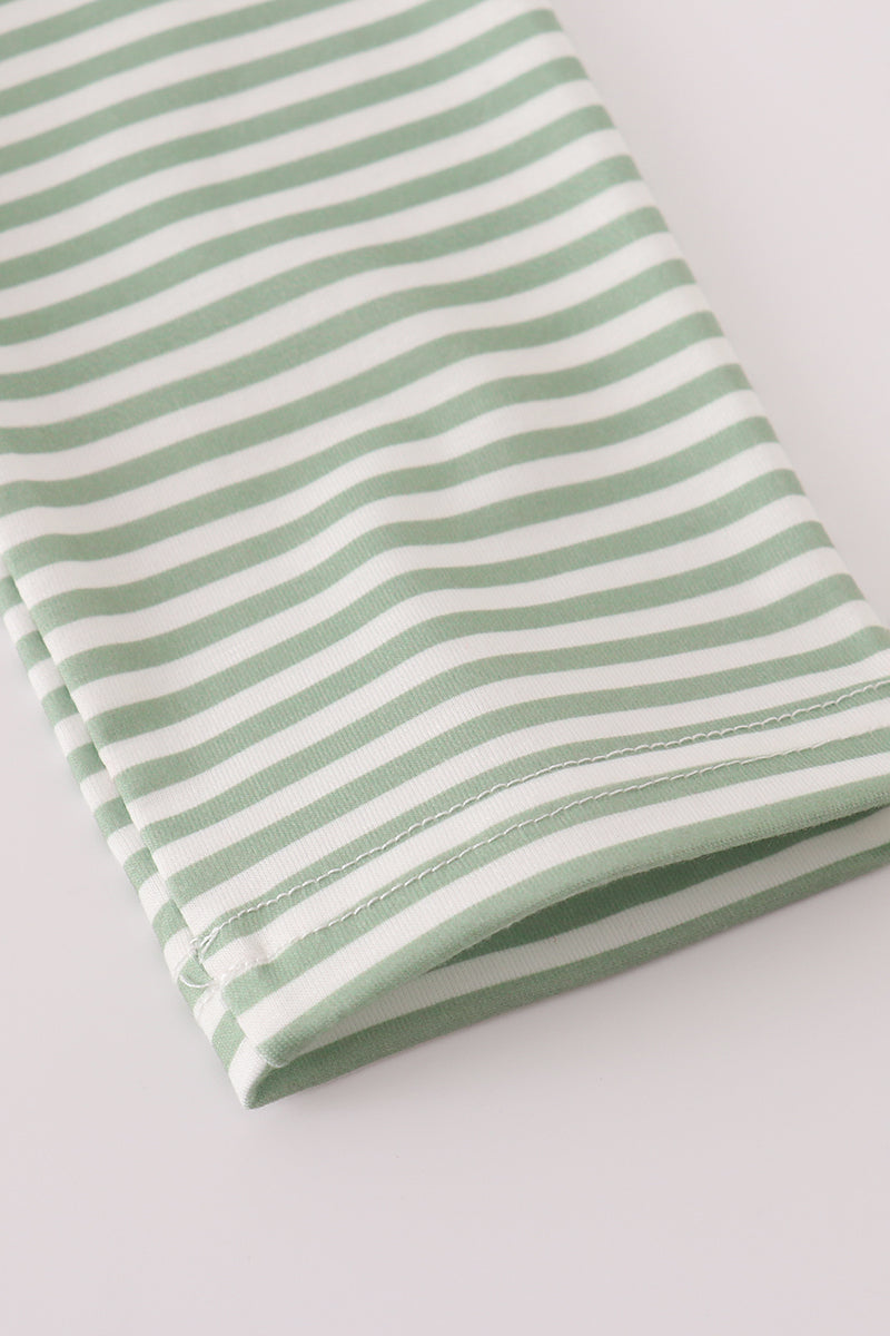 Folded green and white striped fabric on a light gray background