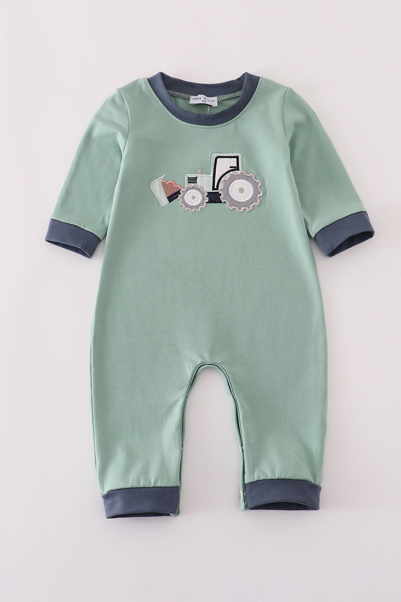 Green baby onesie with tractor design on a light gray background