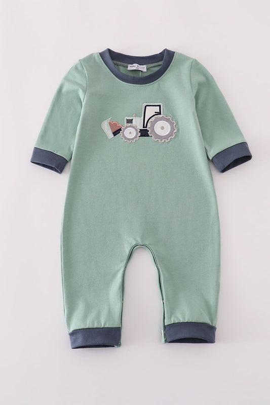 Green baby onesie with tractor design on a light gray background